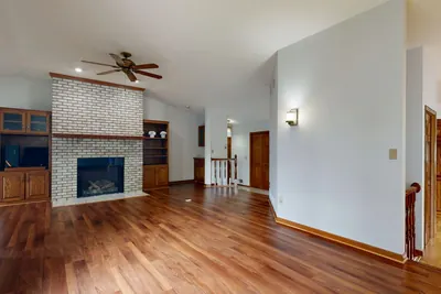 Empty living room with glossy hardwood flooring and a brick fireplace