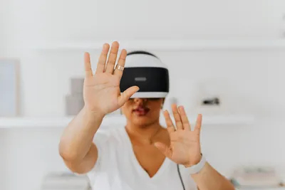Person wearing a head-mounted display and reaching out with both hands